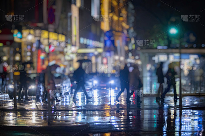 人们穿过雨夜的城市街道