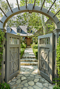 This arch-topped entry gate offers some privacy from the street and frames the approach to the house, which is paved with local flagstone.