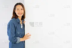 近距离的年轻美丽的亚洲女人微笑与幸福和站与白色的模型背景板为礼物或展示商品，产品或内容背景，广告营销