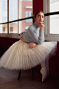 Beautiful ballerina in tutu skirt posing next to window