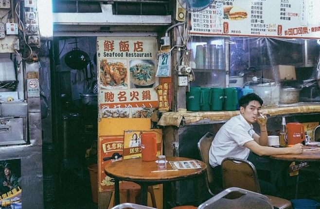 这可能包含：一名男子坐在餐厅前的桌子旁，...
