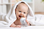 盖着毛巾趴着的拿着奶瓶喝水的婴儿