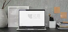 黑色的桌子和灰色的墙壁上有开放式空白屏幕的笔记本电脑和办公用品