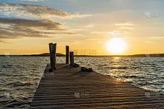 橘色的夏日落日在码头后面的湖边