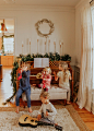 This may contain: three children sitting on a couch playing with musical instruments in front of a christmas tree
