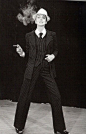 60 年代末，Yves Saint Laurent 设计了轰动时尚界的「吸烟装」，从男装吸取设计灵感运用到女装中，白衬衫，领结，黑色礼服套装，这是时尚界第一套女版西装，粗跟高跟鞋和毛呢礼帽让女性阴柔与男性阳刚并存。
