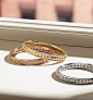 A color photo shows three David Yurman women’s bracelets from the Modern Renaissance collection scattered on a white windowsill with a view of a brick building. The jewelry is crafted from 18K rose or yellow gold with cognac or white diamond accents. One 