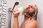 英俊的胡子男人在家里洗澡的时候用洗发水瓶而不是麦克风唱歌。快乐的高加索人一边唱一边用面部表情享受生活