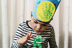 因冠状病毒感染而被监禁的多残障儿童的生日。坐在一个房间里的绿色垫子上，看着蛋糕和头上戴着皇冠的蜡烛