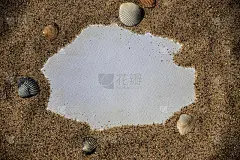 白色的沙子上有一张白纸，上面有贝壳和石头。海上短信，浪漫，情人节，母亲节，父亲节。本空间