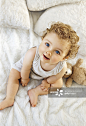 Smiling toddler raising head sat on white blanket