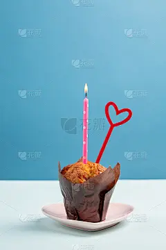 松饼与燃烧的蜡烛和红色的心在蓝色的背景上。小生日蛋糕。