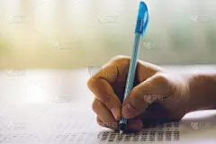 近距离的高中或大学学生拿着一支笔写在答题纸上在考场。大学生在大学的考场里做多项选择题。