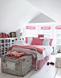 a bed with red and white bedding in the middle of a white room
