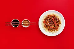 Sweet and sour pork on rice with red peppers, top view, copy spaceStir-fry with chicken meat, vegetables and rice on red background with soy sauce