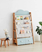 a toy shelf with books and toys in it next to a potted plant on the floor