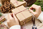 christmas-presents-preparation-gift-box-wrapped-black-white-striped-paper-crate-full-pine-cones-christmas-toys-wrapping-materials-white-wood-old-background
