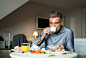 Mature businessman having breakfast in a hotel room.