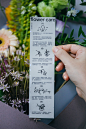 This may contain: a person holding a flower care card in front of a bunch of flowers with chinese writing on it
