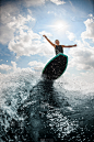 女人在冲浪板上跳跃，在河上冲浪，对着乌云的天空