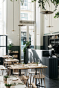 The interior of the restaurant still has the open, vegetal feeling of the overgrown factory, with tall ceilings and long pendant lights and vines trailing from the rafters. Cladding, painted in shades of dark green and black, grounds the space.