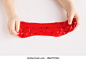 Child stretching colorful red slime to the sides. Kids hands playing slime toy on white background. Making slime. Top view. Flatlay 库存照片