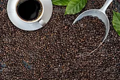 黑木桌的背景上放着一杯咖啡和豆子。俯视图