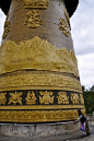 Woman spinning a huge prayer wheel in Gyelthang