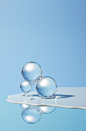 small balls floating in the center of an empty mirror, in the style of sculptural volumes, light blue, minimalist landscapes, transparency, baroque-inspired still lifes, clean and simple designs, water drops