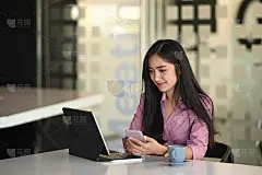 一个女商人在办公室专注于电脑平板电脑和手握手机。