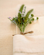 Menus tucked into linen napkins look lovely with a petite bunch of wildflowers.