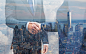 Two people shaking hands with New York skyline