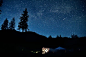 A shooting star travels across the starry night above a lighted tent in Golden.