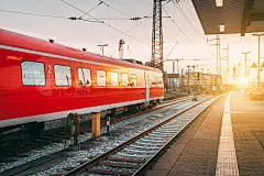 Beautiful railway station with modern red commuter train at sunset