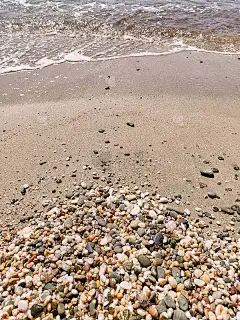海卵石，海泡沫，海浪，灿烂的阳光。前视图。海洋背景。景观壁纸和自然概念。摘要风格的文本，设计，时尚，