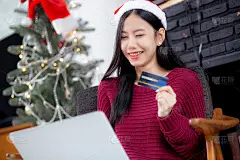 年轻的亚洲女性网购用信用卡在笔记本电脑上，女性购物用借记卡支付，圣诞节在过节，新年快乐，顾客用购物到