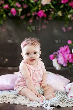 一个漂亮的小女孩带着粉红色的花。甜美微笑的女孩坐在地板上