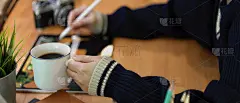 女性左手拿着咖啡杯，右手在电脑上工作