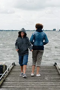 一个阴天的夏日，木码头上的女人和女孩。那个女人站在后面，而那个女孩正走向摄像机。家庭的概念