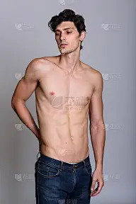 工作室拍摄的年轻英俊男子摆姿势，同时低头看赤膊