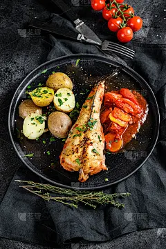 番茄烤安康鱼配土豆和蔬菜。黑色背景。俯视图