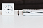 A clock, a notebook and a smartphone on a white desk