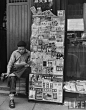 1947年，上海。认真读报的书报摊小贩，他穿着牛仔裤和新式皮鞋。他的书报摊上摆 满了从美国的TIME到中华民国国内自由出版的各类书报。