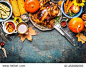 Festive  Thanksgiving Day food background with roasted whole turkey or chicken and sauce, harvest vegetables: corn, pumpkin,carrots with cutlery on dark rustic kitchen table, top view, border