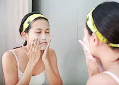 Woman applying foam cream to face reflect with bathroom mirror.