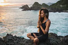 年轻女子独自祈祷和冥想在日落与美丽的海洋和山景。自我剖析和自我反省。精神和情感的概念。反省、内向和灵