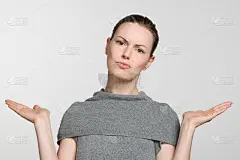 穿着灰色毛衣的年轻女子用手臂做了一个不知道的手势