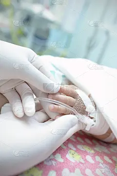 戴着手套的手牵着婴儿的手。疾病，关怀的象征。