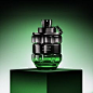 This may contain: a green and black bottle on top of a box with a chain hanging from it