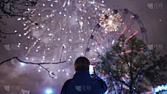一个人在室外用智能手机拍摄烟花爆炸的特写剪影